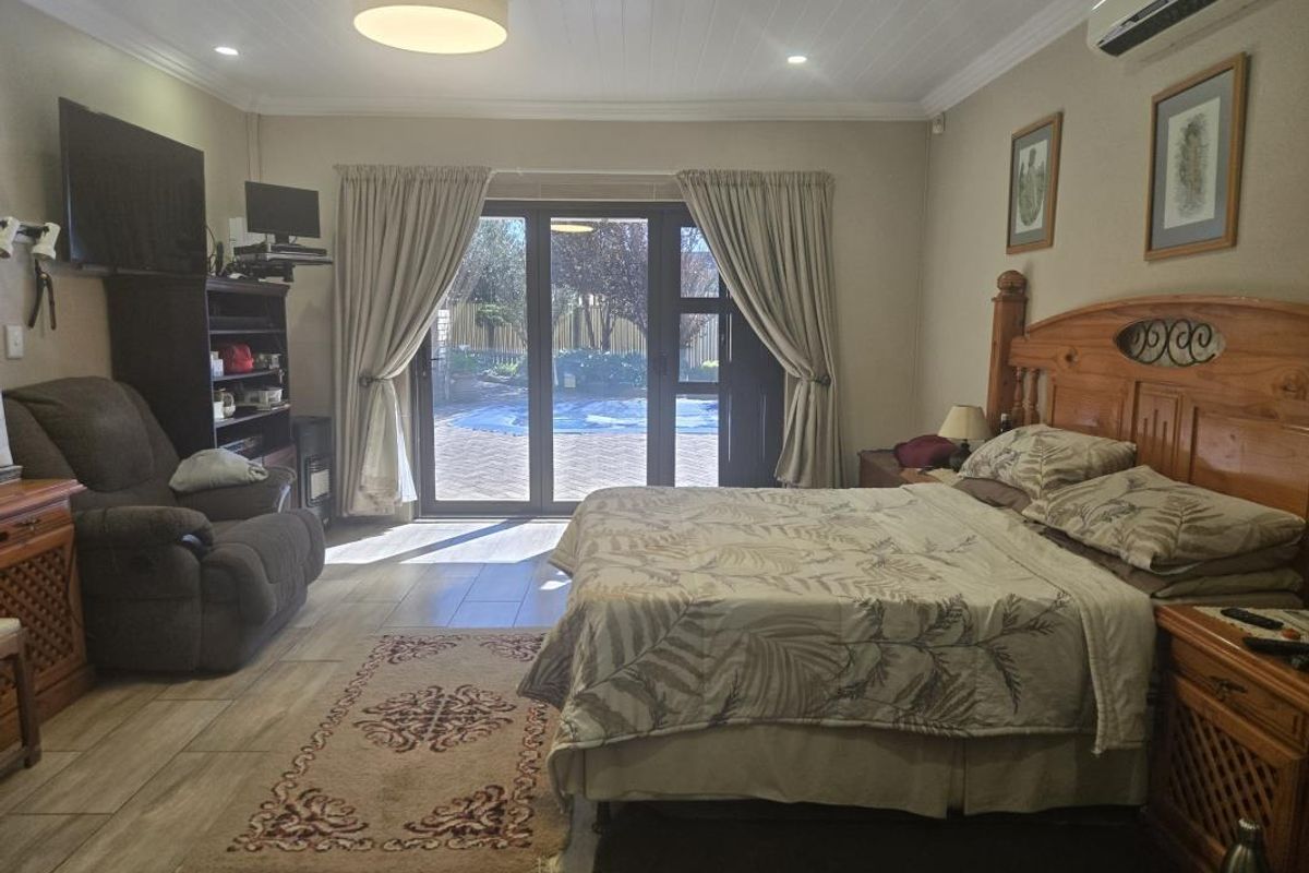Spacious bedroom featuring tiled flooring, a tongue and groove ceiling, and sliding glass doors providing direct access to the outdoor pool area.