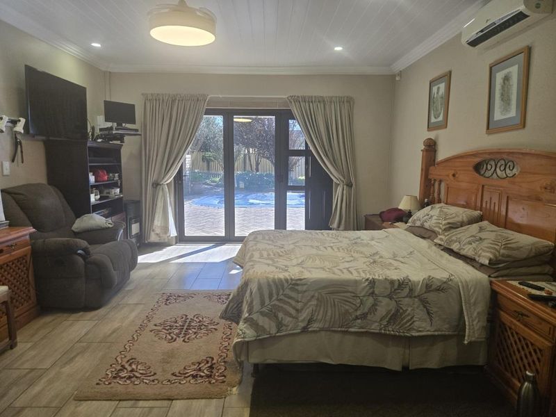 Spacious bedroom featuring tiled flooring, a tongue and groove ceiling, and sliding glass doors providing direct access to the outdoor pool area.