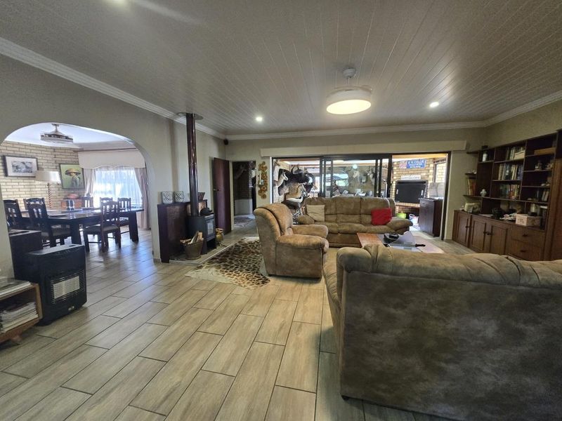 Spacious open-plan living and dining area featuring tiled floors, a wood-burning fireplace, and direct access to an outdoor patio through sliding glass doors.