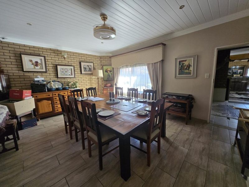 A dining room featuring an exposed brick feature wall, tiled flooring, and a tongue and groove ceiling with a central fan.