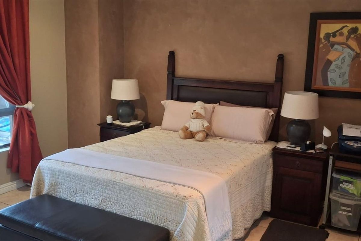 A bedroom featuring tiled flooring and a large window with natural light, providing a comfortable space for rest.