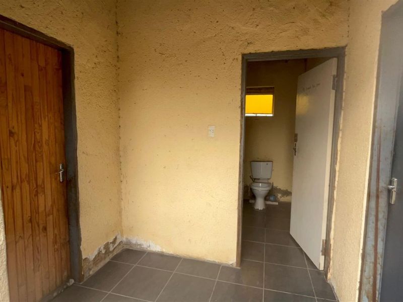 A small interior space featuring tiled flooring and access to an adjoining bathroom with a toilet.