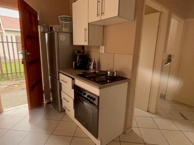 Compact kitchen area featuring built-in cabinetry, a fitted oven and hob, and direct access to the exterior.
