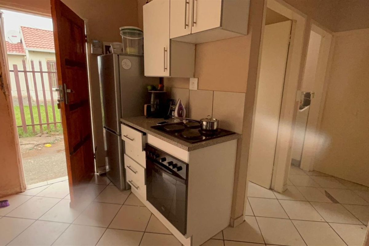 Compact kitchen area featuring built-in cabinetry, a fitted oven and hob, and direct access to the exterior.