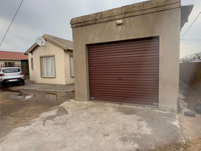 Exterior view of a detached single-car garage with a roller shutter door, situated on a concrete driveway adjacent to the main residence.