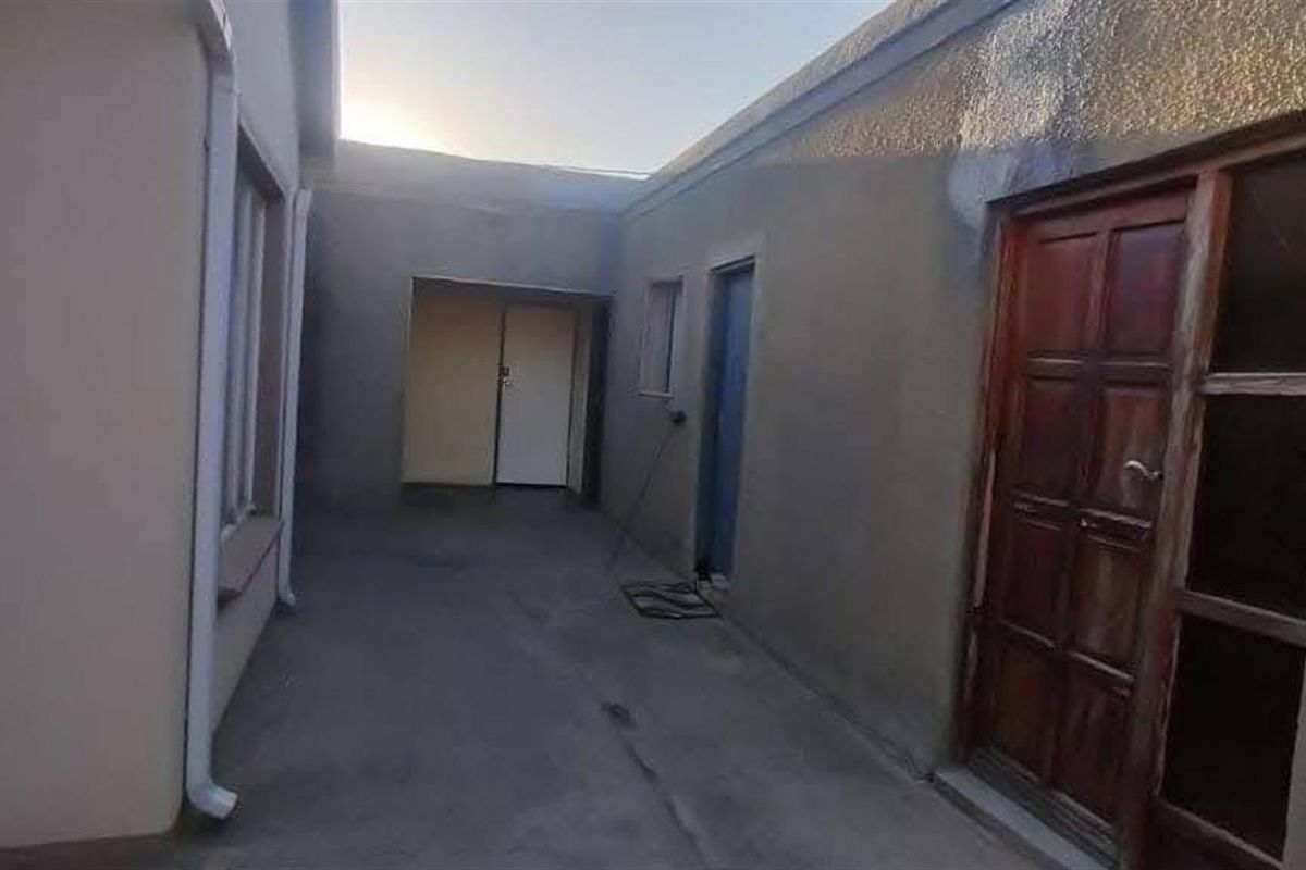 A view of the rear exterior courtyard area featuring concrete paving and multiple access points to the dwelling.