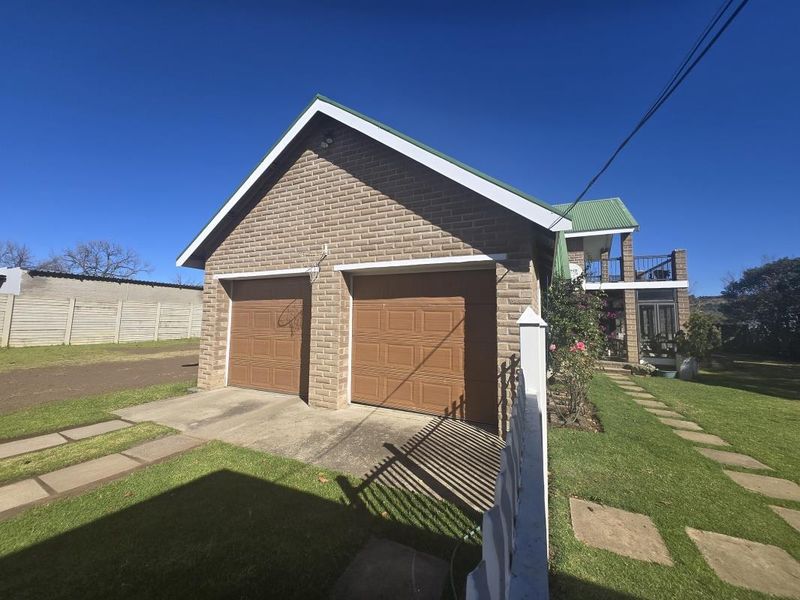 A detached double garage with a brick facade, concrete driveway, and well-maintained lawn area.