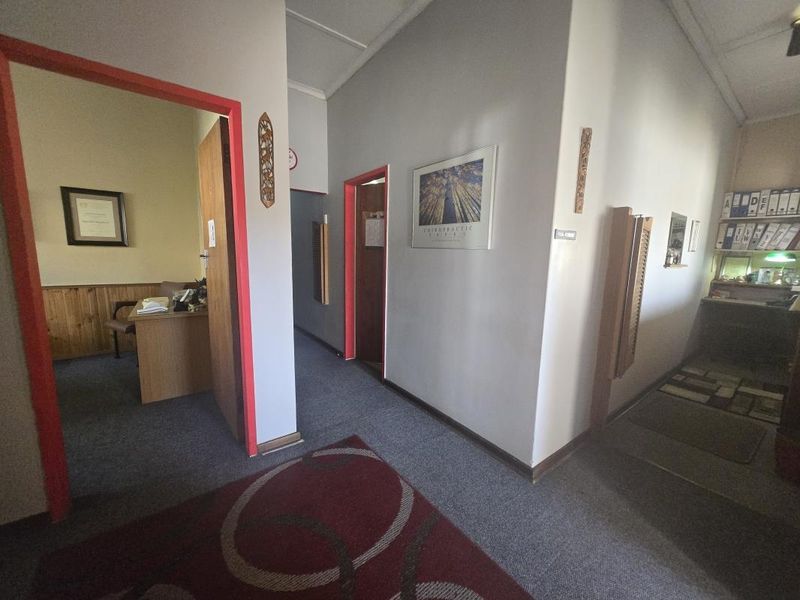 A commercial hallway featuring carpeted flooring and timber wall paneling, providing access to multiple office rooms.