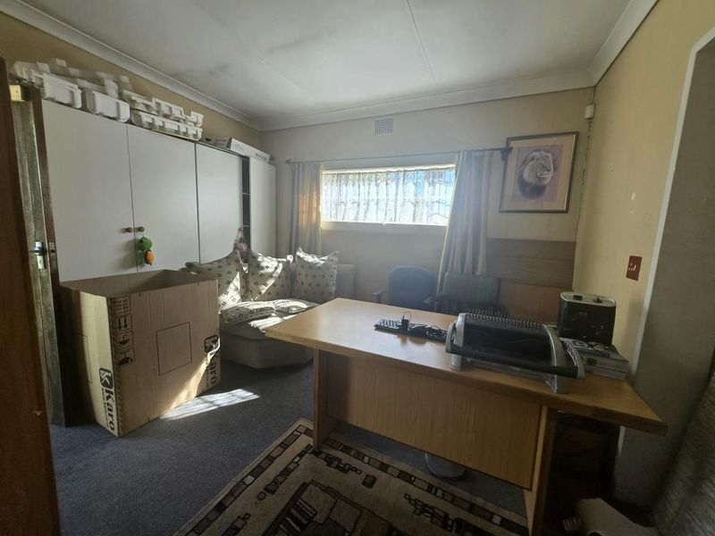 A functional office space featuring built-in storage cupboards, a horizontal window, and coved ceiling details, currently used as a workspace.