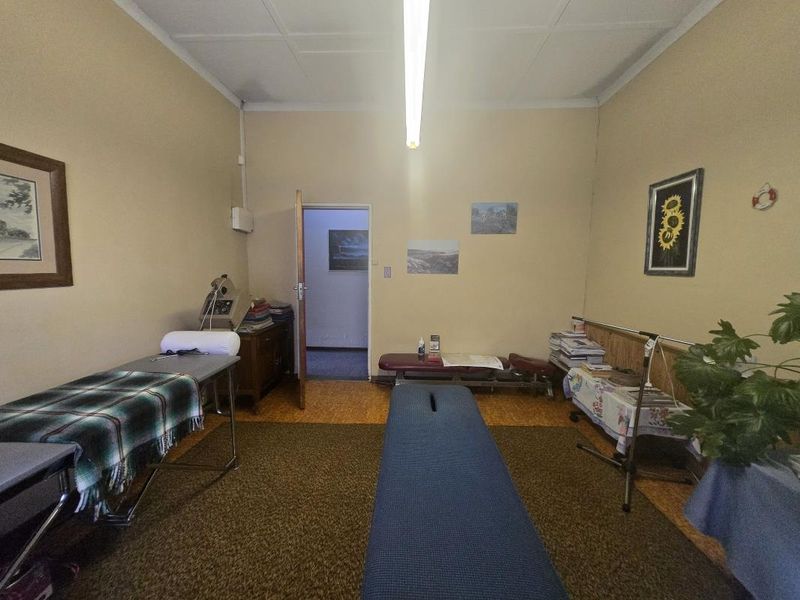 A functional office or treatment room featuring cork flooring, timber wall paneling, and overhead fluorescent lighting.