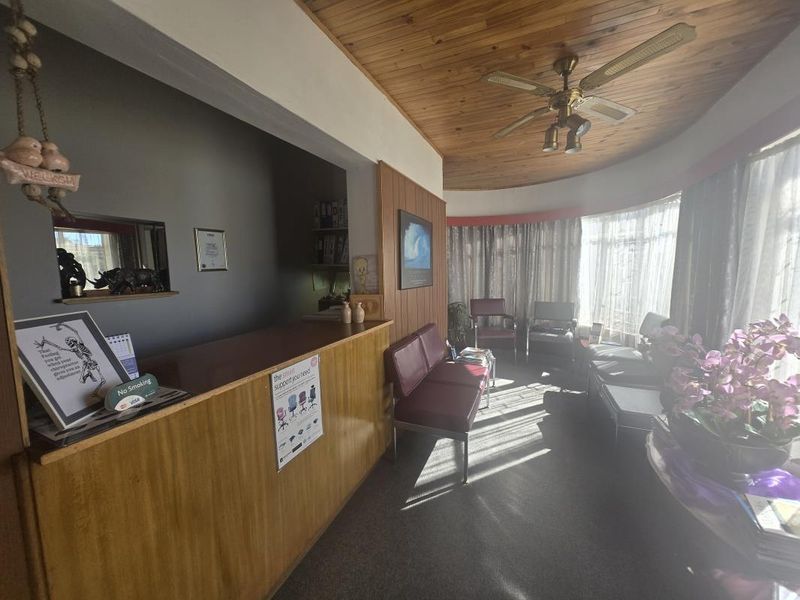 Commercial reception area featuring a built-in wooden desk, timber ceiling with fan, and wood paneling accents.