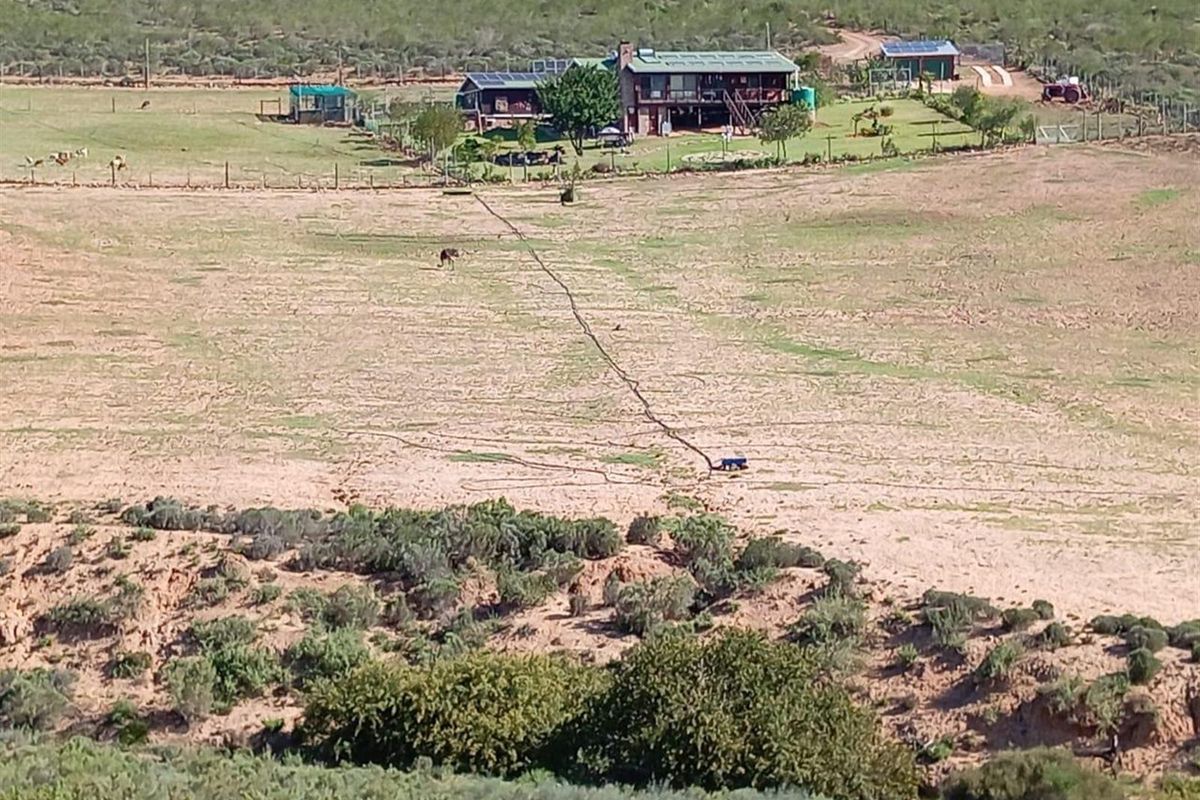 An elevated aerial view of a rural farm property featuring a main dwelling, outbuildings, and expansive surrounding grazing land.