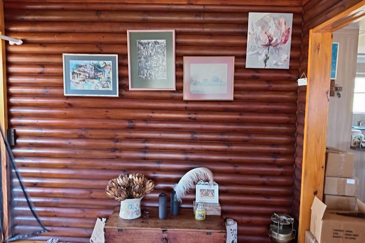 Interior view of a living area featuring rustic log-style timber wall paneling and wooden flooring.