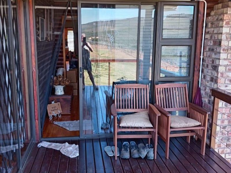 Covered timber deck patio featuring sliding glass doors, brick accents, and log-style wall cladding, offering a rustic outdoor living space.