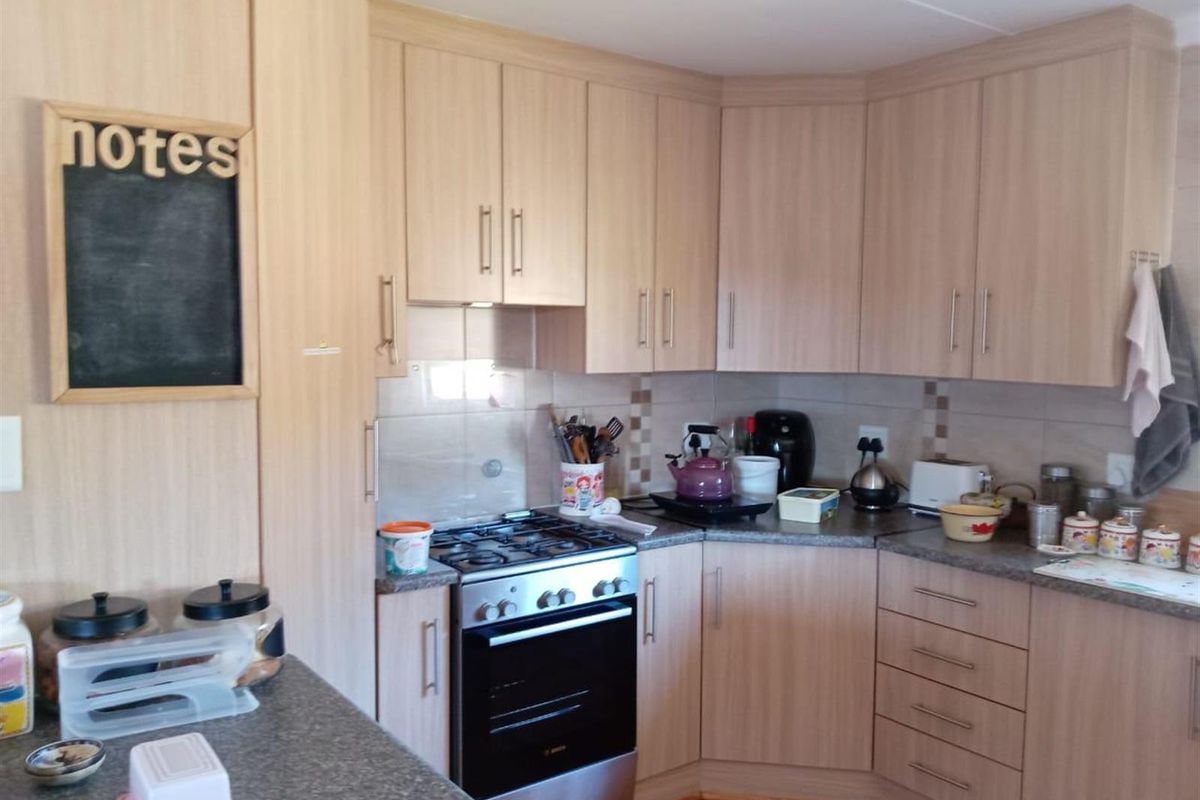 A functional kitchen featuring light wood-grain cabinetry, granite-look countertops, tiled splashbacks, and a built-in gas stove with an oven.