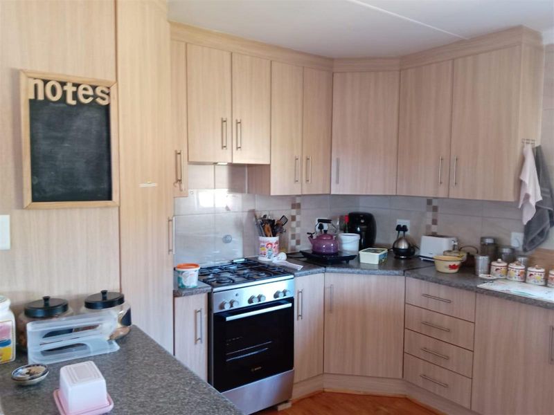 A functional kitchen featuring light wood-grain cabinetry, granite-look countertops, tiled splashbacks, and a built-in gas stove with an oven.