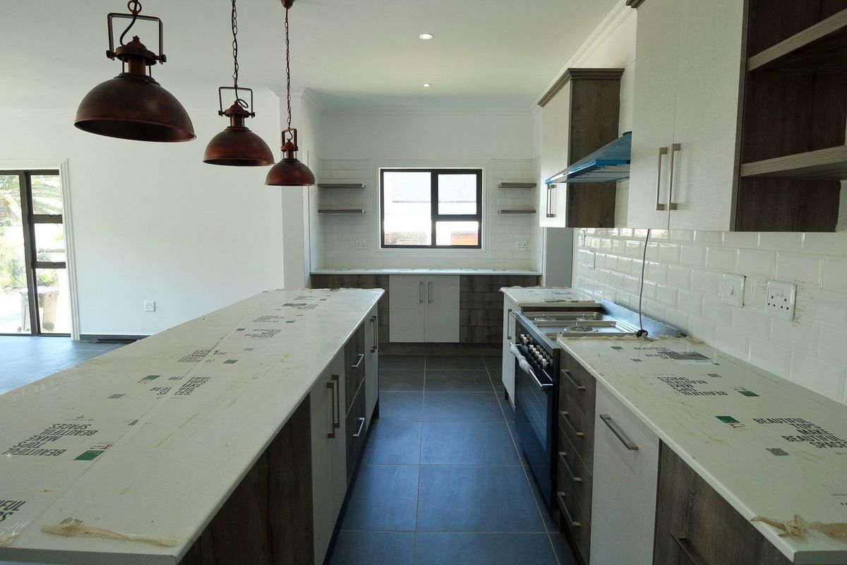 Modern kitchen featuring a central island, stone countertops, subway tile backsplash, and dark wood cabinetry with integrated appliances and stylish pendant lighting.