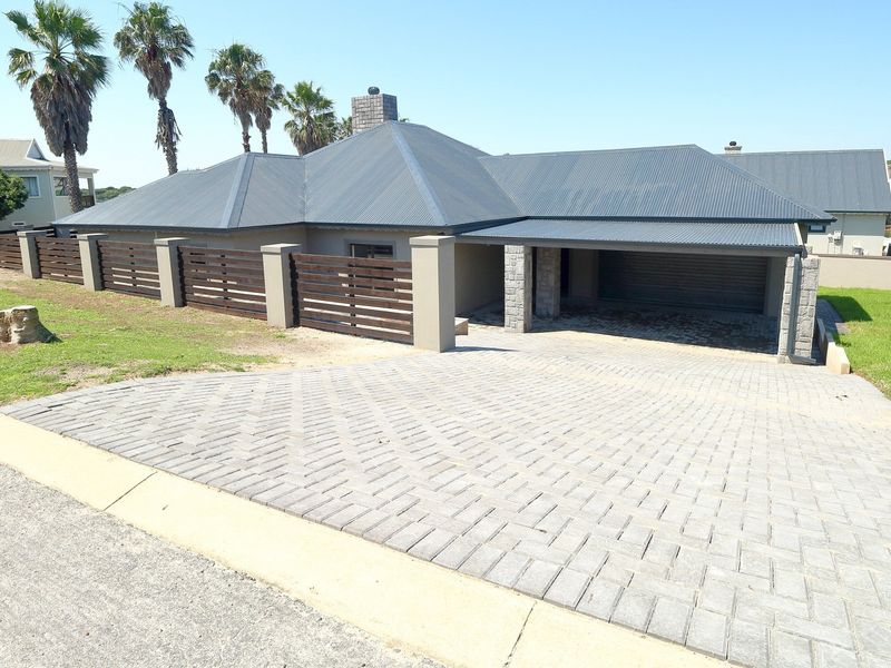 Front elevation of a modern house featuring a paved driveway, double garage, and timber slat fencing with masonry pillars.