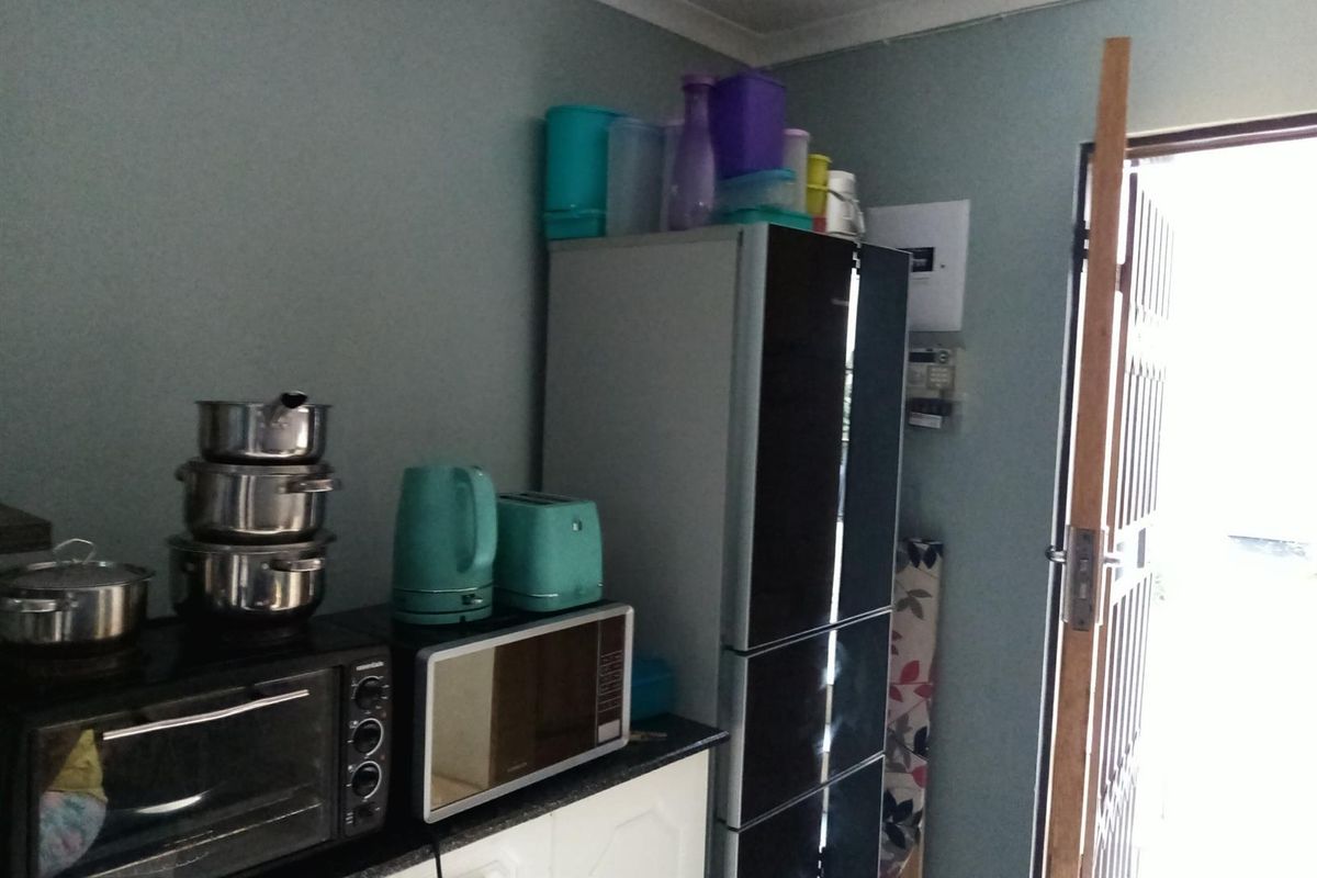 A functional kitchen area featuring built-in cabinetry, countertop space, and an accessible electrical distribution board near the exterior door.