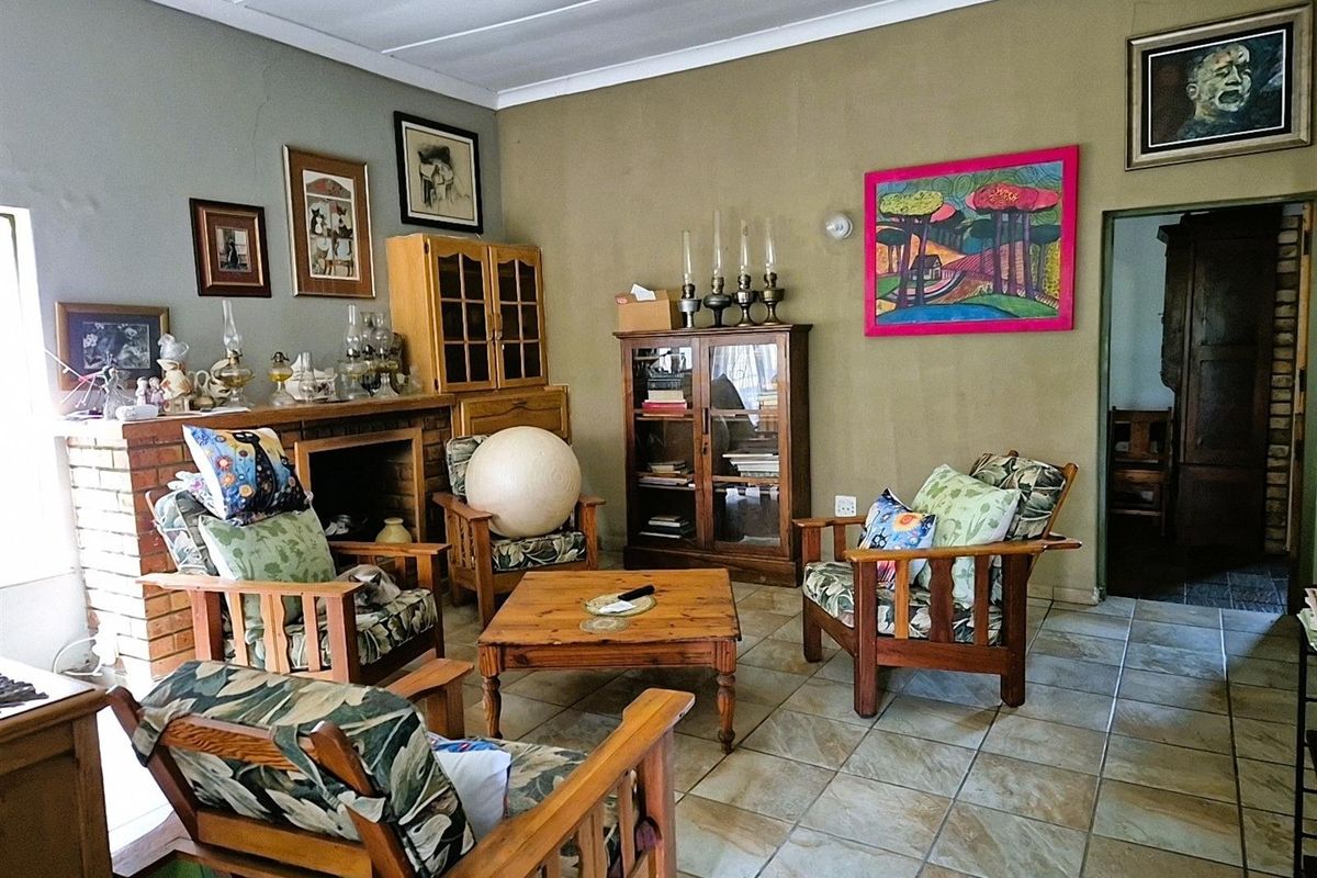 A living room featuring a brick fireplace, tiled flooring, and access to an adjacent room, offering a traditional and lived-in atmosphere.