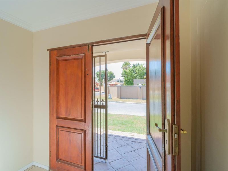 Entrance area featuring double wooden doors and a security gate, opening onto a paved porch with views of the street.
