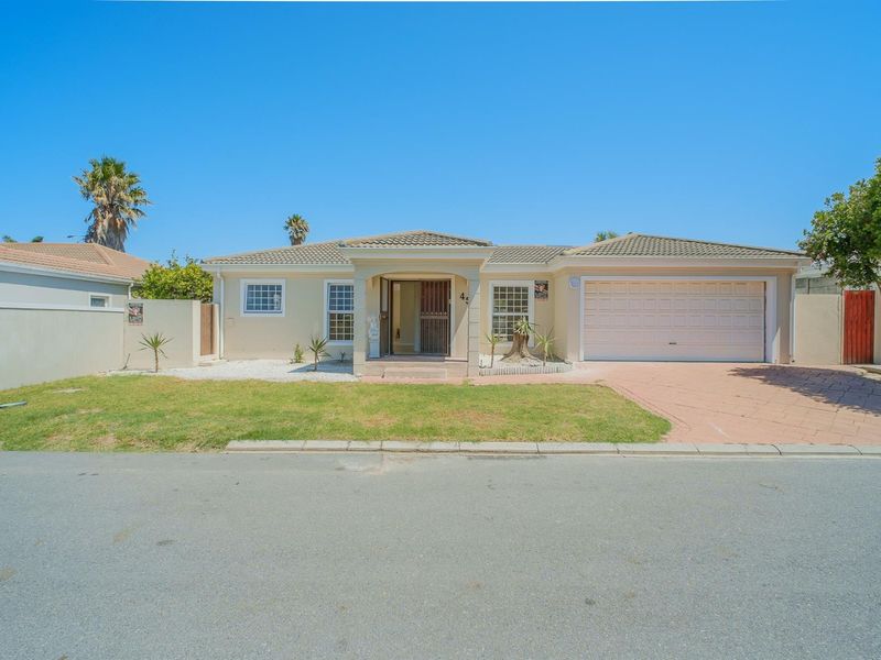 Front elevation of a single-story house featuring a paved driveway, integrated garage, and a well-maintained front garden with boundary wall.