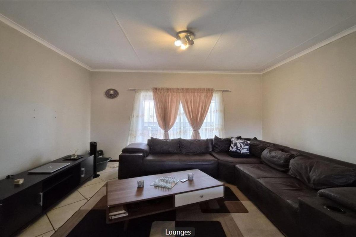 A comfortable living room featuring tiled flooring, neutral wall finishes, and a central ceiling light fixture.