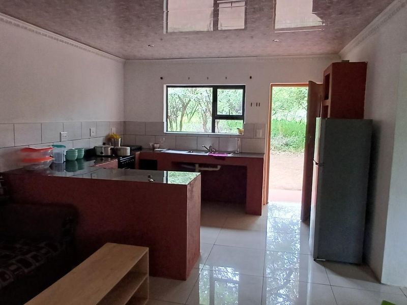 Open-plan living area featuring a kitchen with built-in counters, tiled flooring, and direct access to the exterior.