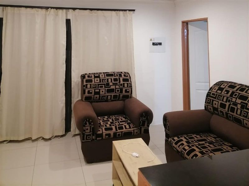 A living room area featuring tiled flooring, neutral walls, and a sliding door with curtains leading to an outdoor space.