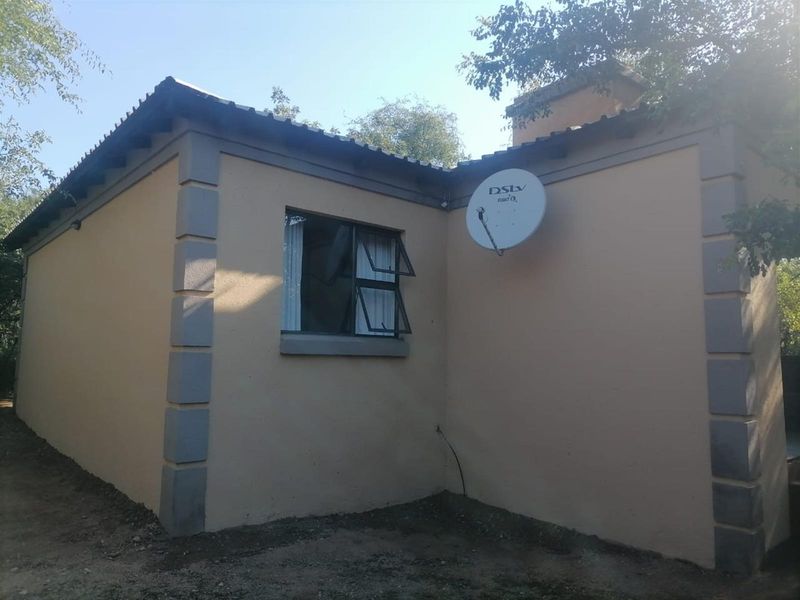 Exterior view of the property showing the side facade, featuring a satellite dish, window with security frame, and corner quoins.