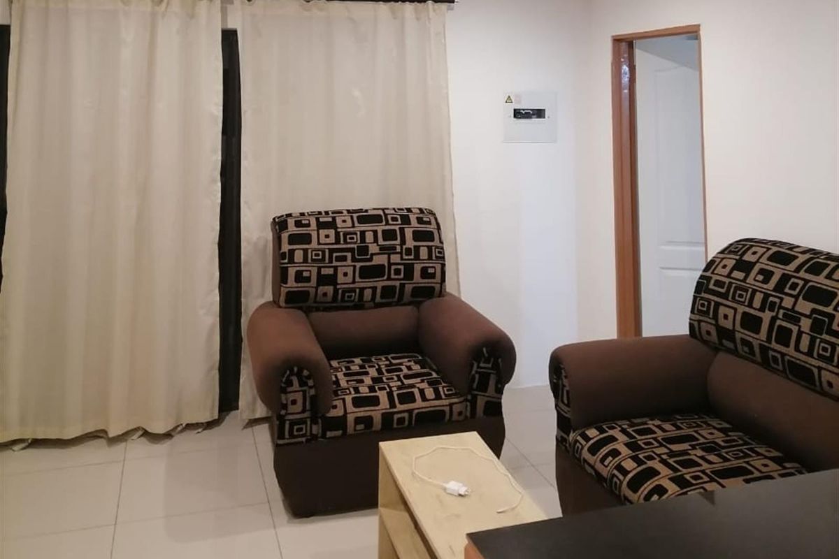 A living room area featuring tiled flooring, neutral walls, and a sliding door with curtains leading to an outdoor space.
