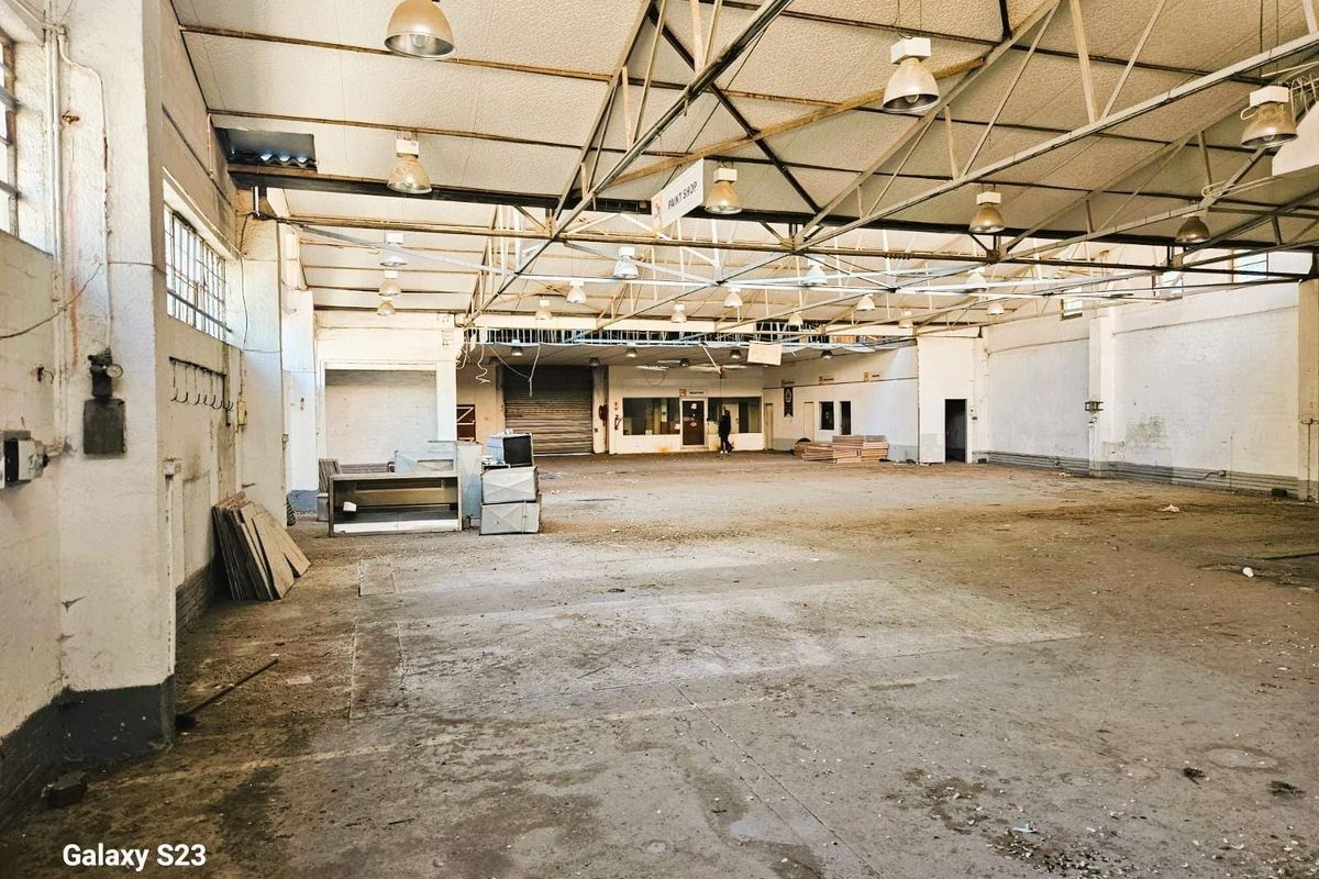 Spacious industrial warehouse featuring high exposed steel truss ceilings, concrete flooring, and large open-plan layout suitable for commercial or manufacturing use.