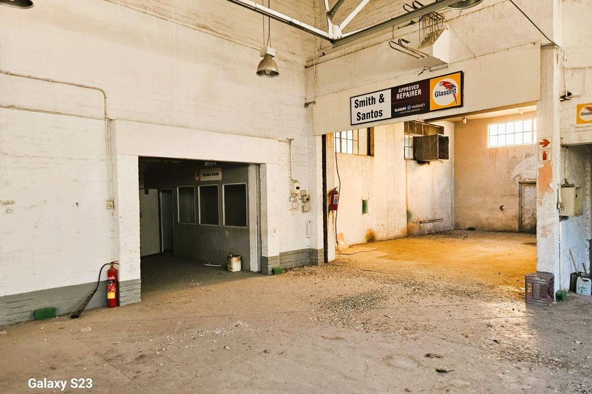 Spacious commercial workshop area featuring high ceilings, industrial lighting, and a dedicated partitioned office or mixing room space.