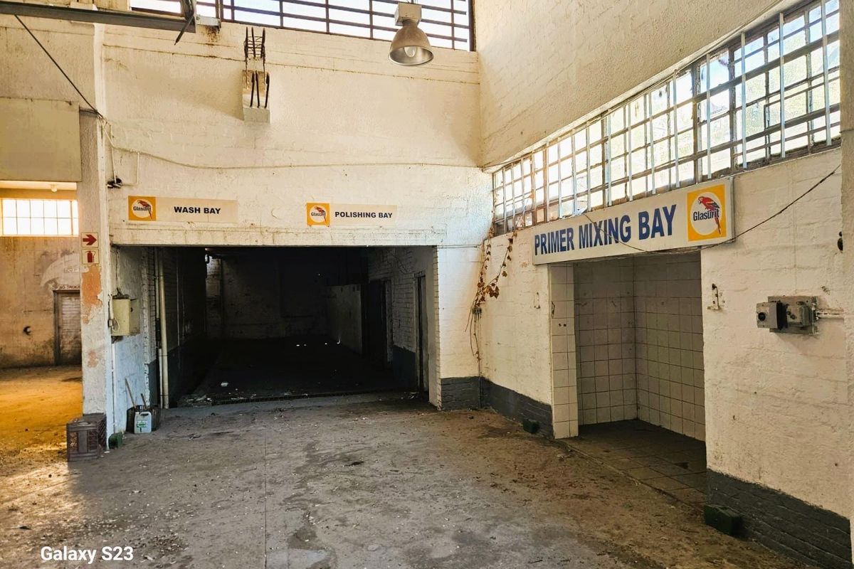 Industrial commercial space featuring designated wash, polishing, and primer mixing bays with high ceilings and exposed brickwork.