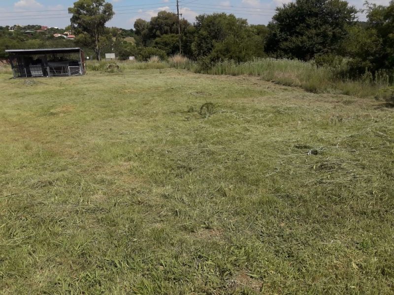 A view of a vacant residential plot featuring cleared grass and a small metal enclosure structure.