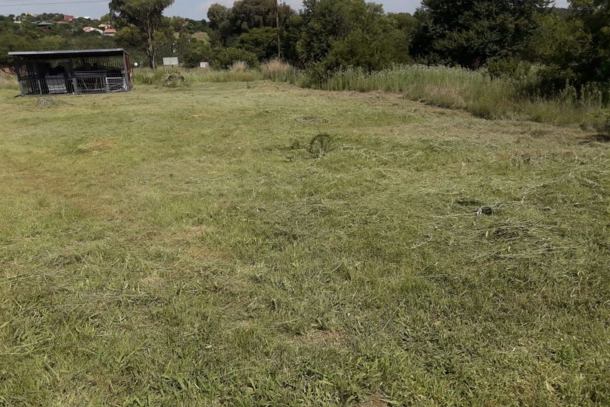 A view of a vacant residential plot featuring cleared grass and a small metal enclosure structure.