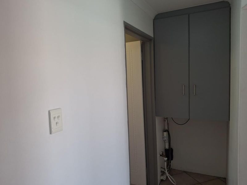 A functional laundry area featuring built-in overhead cabinetry and dedicated plumbing connections for laundry appliances.