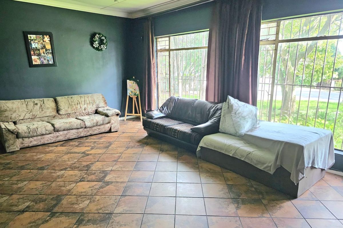 Spacious living room featuring large windows with security bars, dark painted walls, and tiled flooring, offering a bright and functional living space.