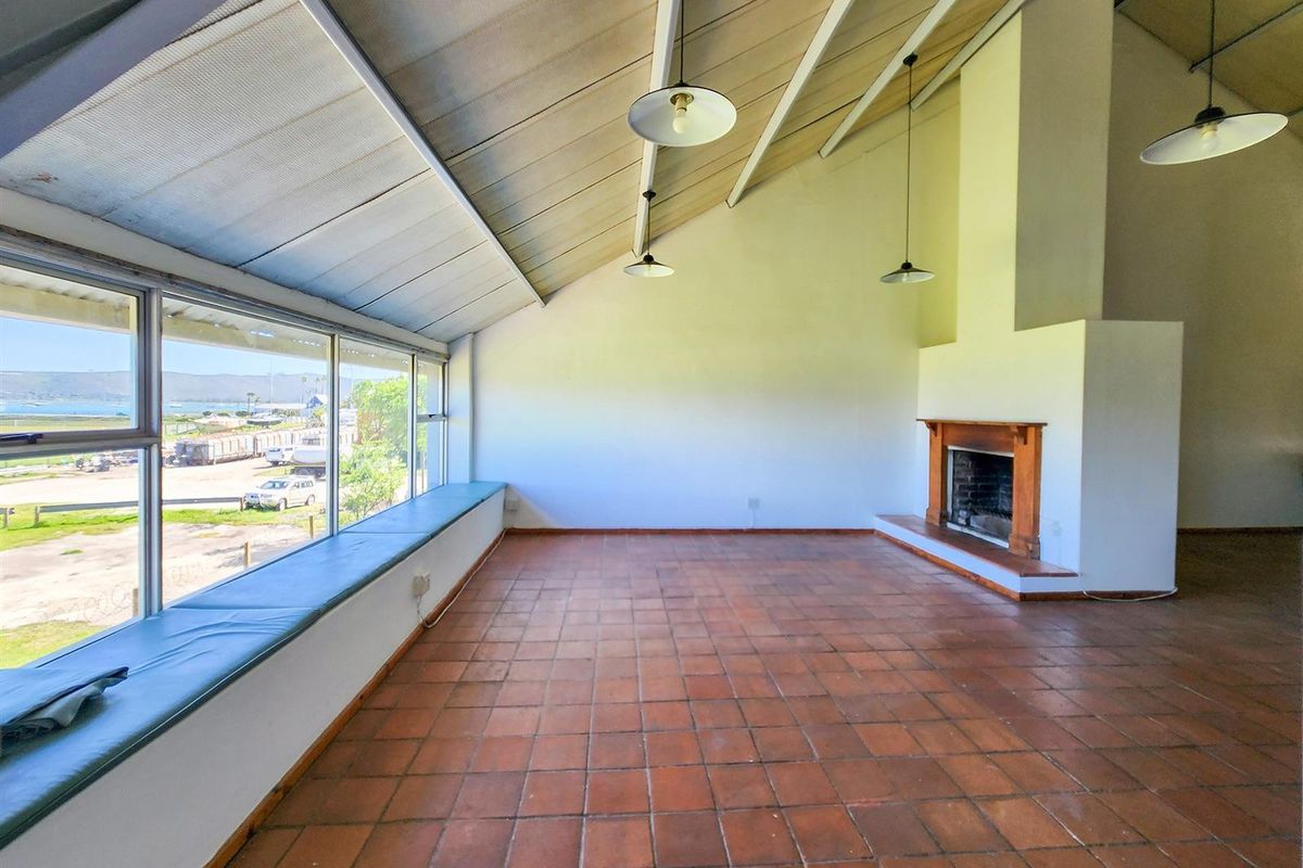 Spacious living area featuring vaulted ceilings, terracotta floor tiles, a built-in fireplace, and large windows offering expansive views.