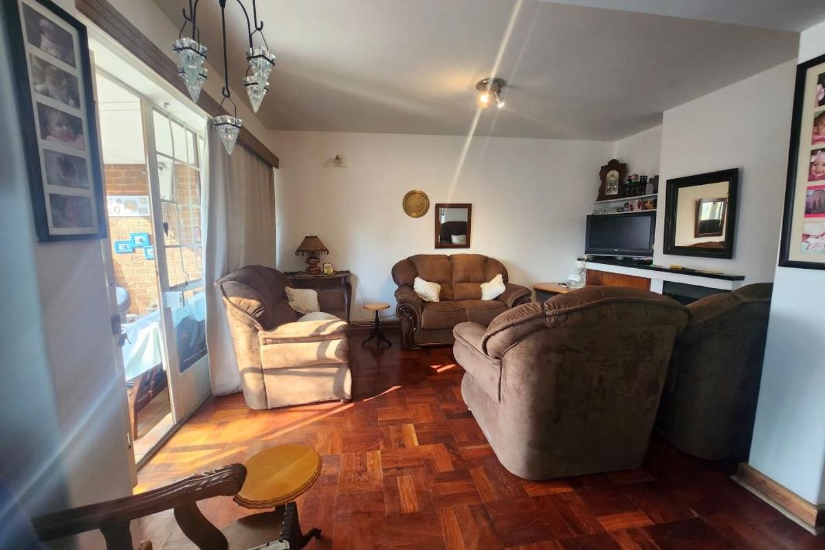 A cozy living room featuring warm parquet flooring, a fireplace, and a sliding glass door providing access to the outdoor area.