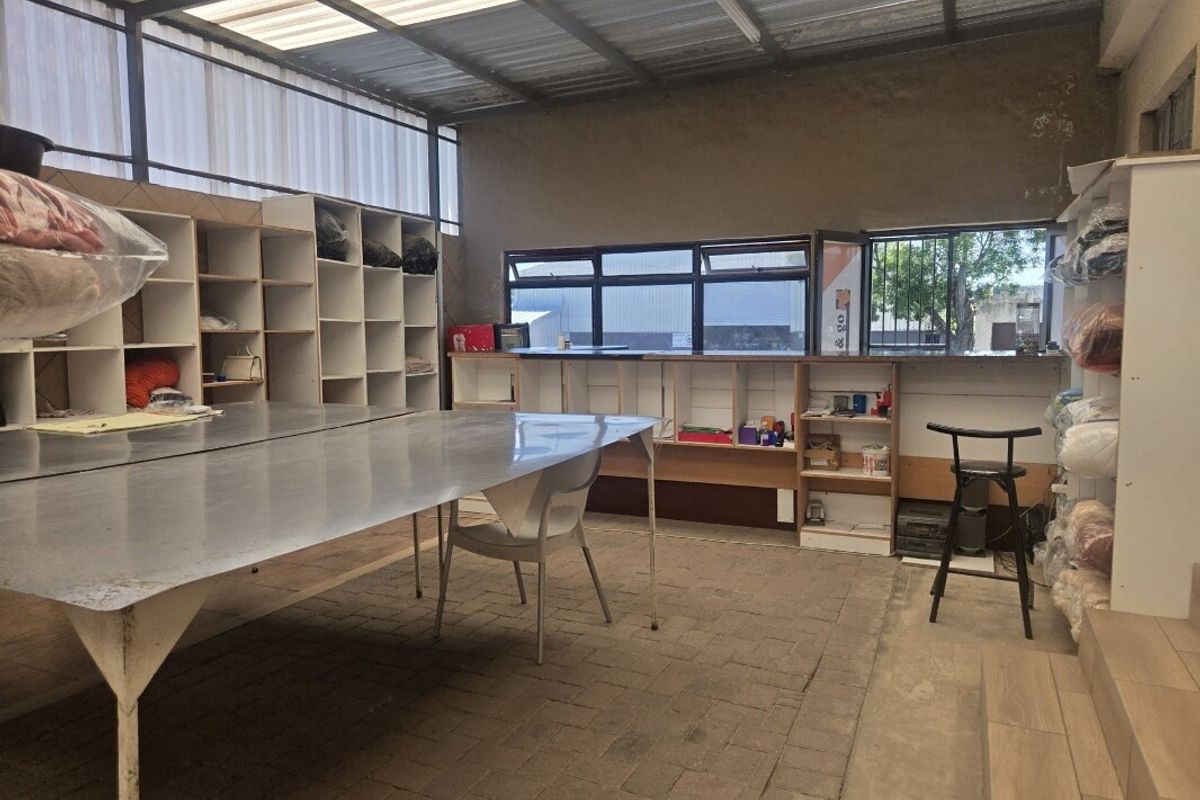 Functional utility or workshop space featuring built-in shelving, a large metal work table, and translucent roof panels providing natural light.