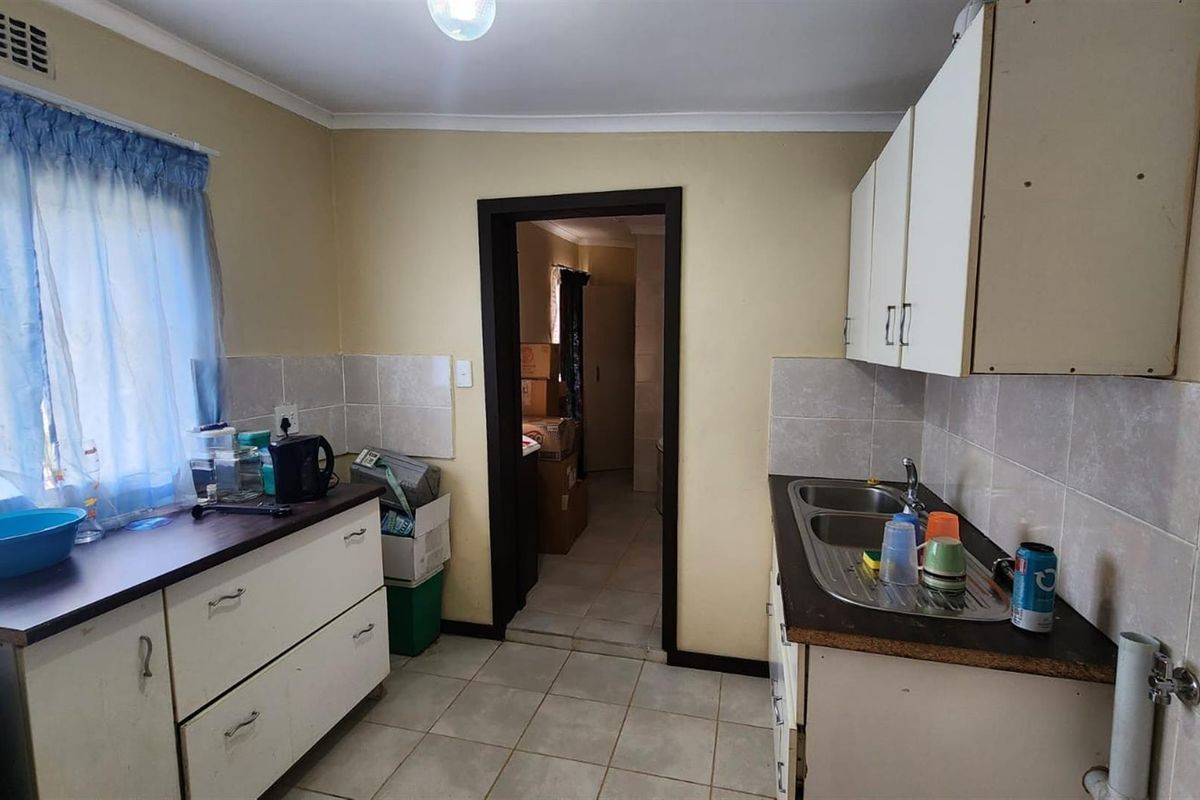 A functional kitchen featuring white cabinetry, a double-basin stainless steel sink, and tiled splashbacks, offering a practical layout for daily meal preparation.