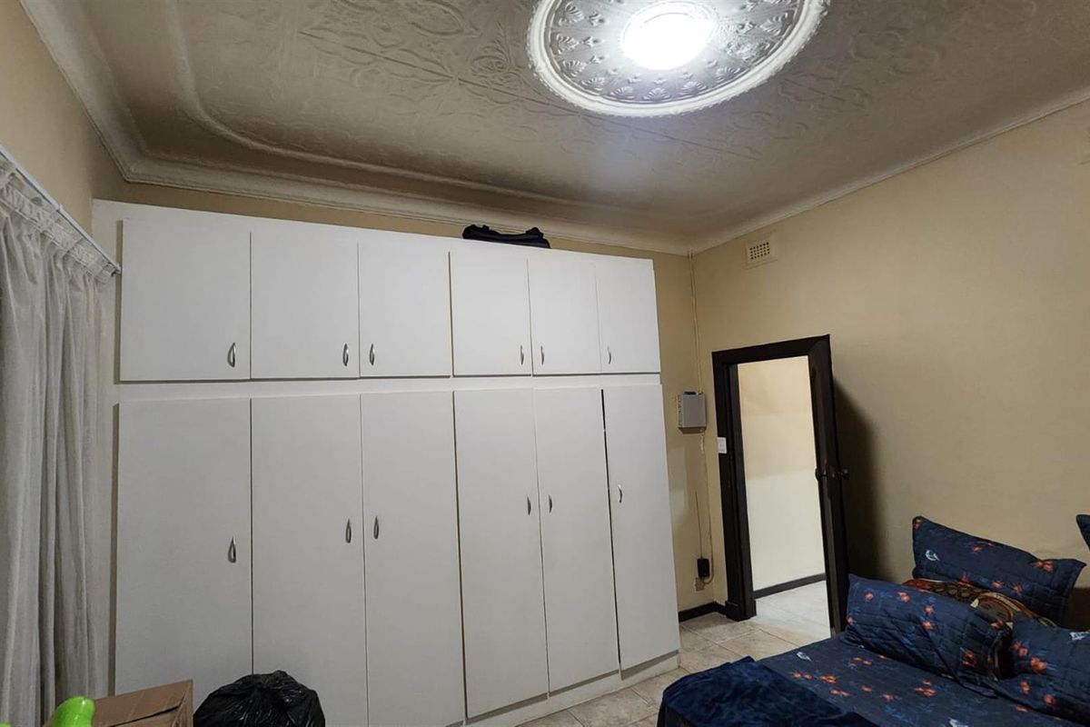 A bedroom featuring extensive floor-to-ceiling built-in cabinetry, decorative ceiling rose, and tiled flooring.