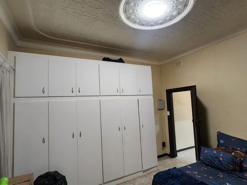 A bedroom featuring extensive floor-to-ceiling built-in cabinetry, decorative ceiling rose, and tiled flooring.