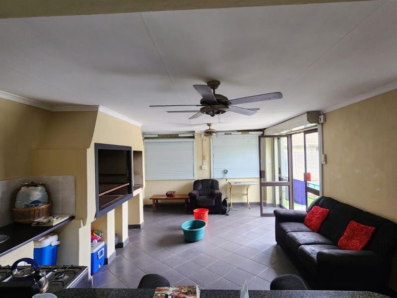 An open-plan living and entertainment area featuring a built-in indoor braai, tiled flooring, and direct access to the outdoor space.