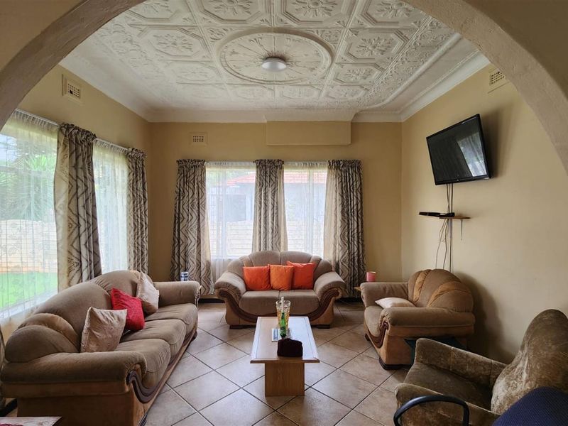 A traditional living room featuring a decorative coffered ceiling, tiled flooring, and an arched entryway, providing a classic and comfortable living space.