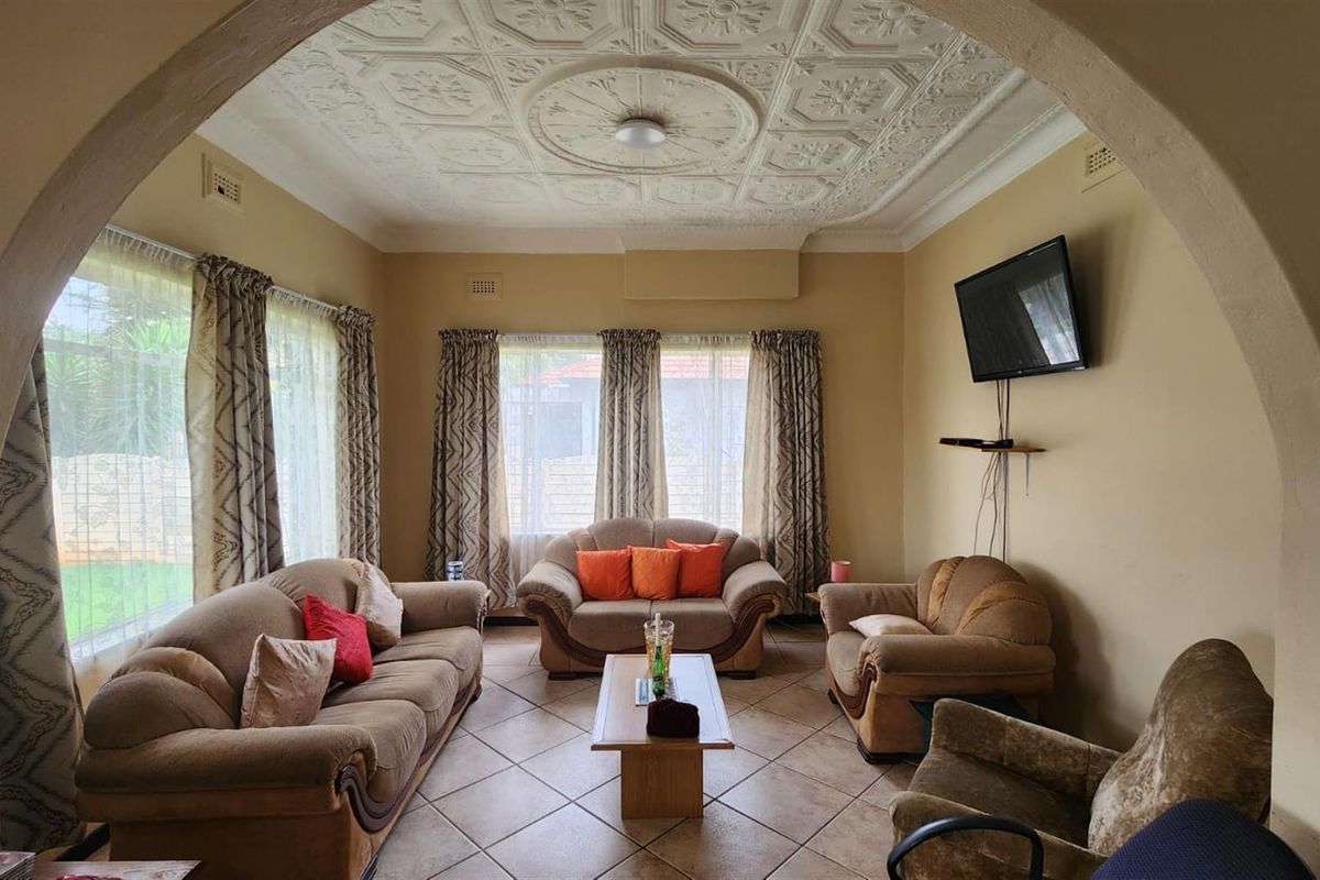 A traditional living room featuring a decorative coffered ceiling, tiled flooring, and an arched entryway, providing a classic and comfortable living space.