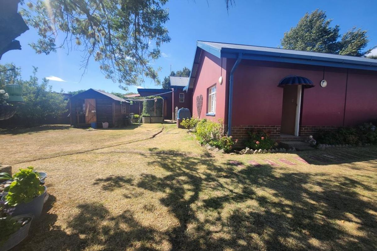 Rear view of the property featuring a lawn, a detached timber garden shed, and the rear facade with brick foundation and metal roofing.