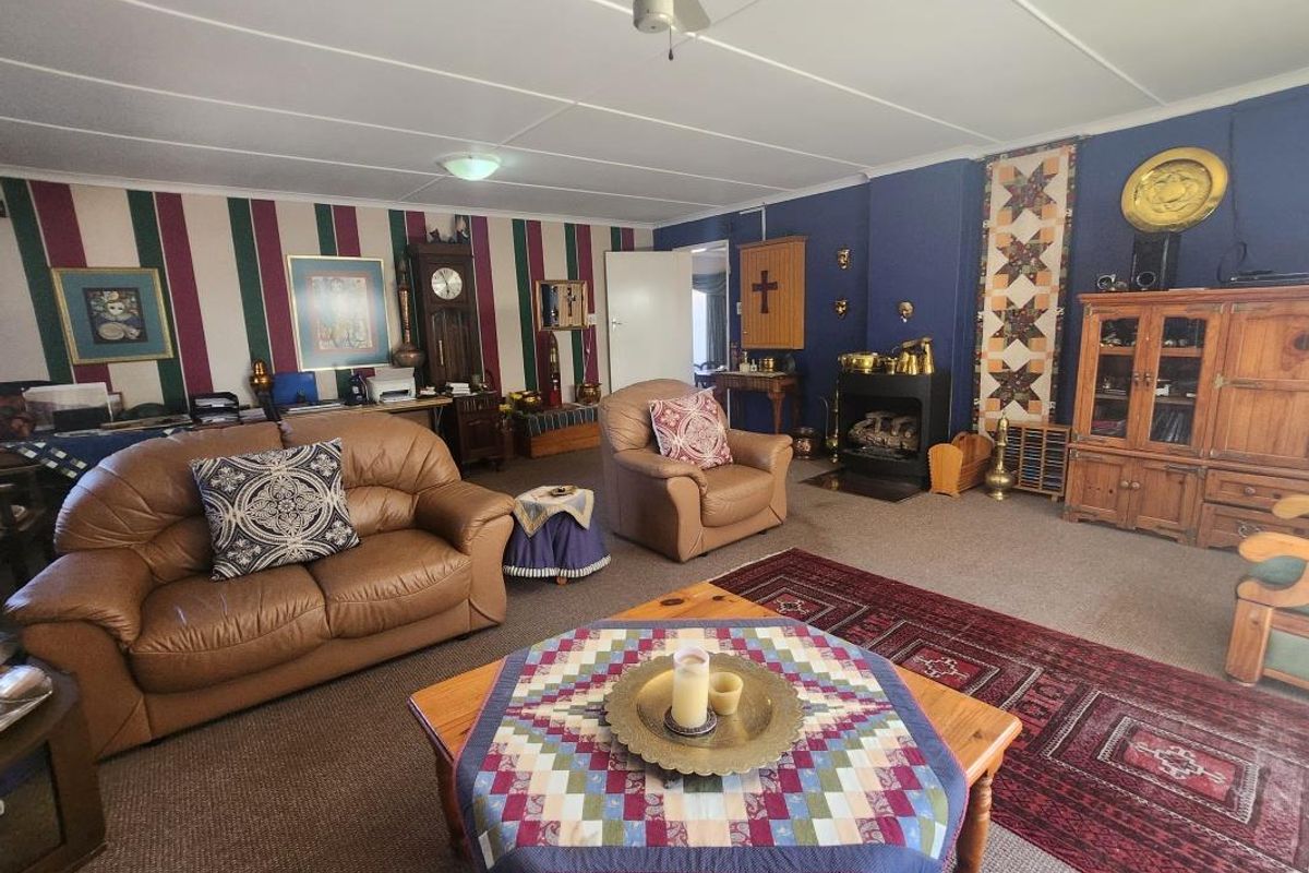 Spacious living room featuring a built-in fireplace, ceiling fan, and carpeted flooring, offering a comfortable and traditional layout.