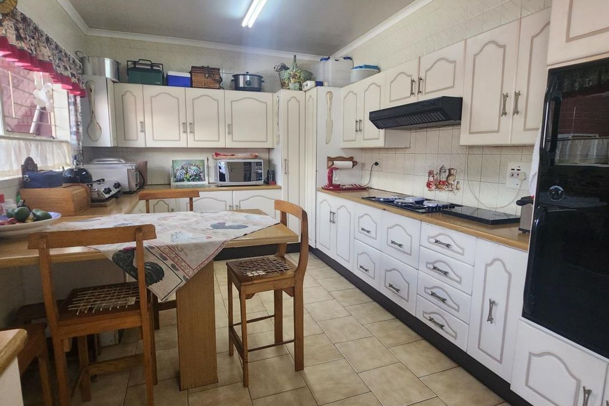 A functional kitchen featuring traditional cabinetry, tiled backsplash, and integrated appliances, offering a classic layout with potential for modern cosmetic updates.